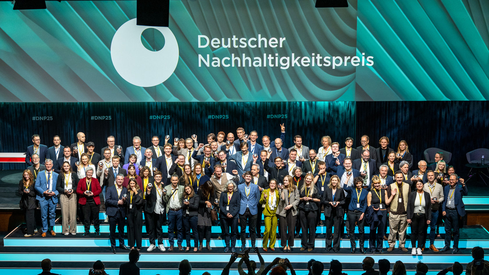 Ryhmäkuva Deutsche Nachhaltigkeitspreis -palkinnon voittajista suurella LED-kankaalla