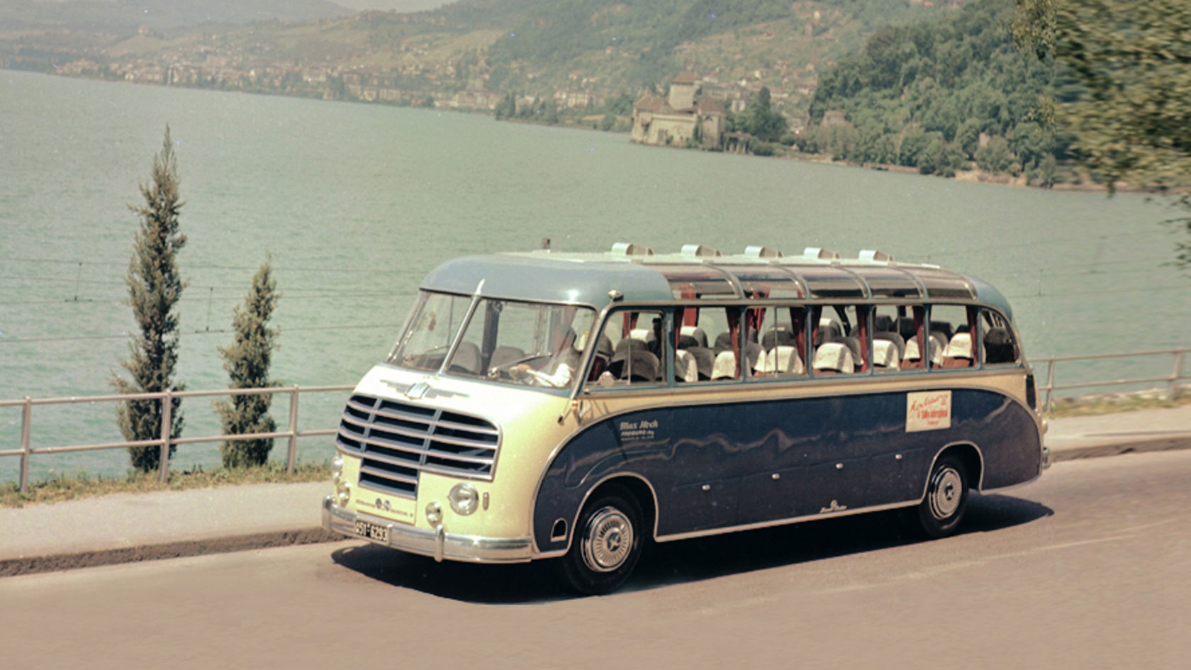 Historic Setra bus driving along the shore of the lake, side view in front of mountain landscape and lake