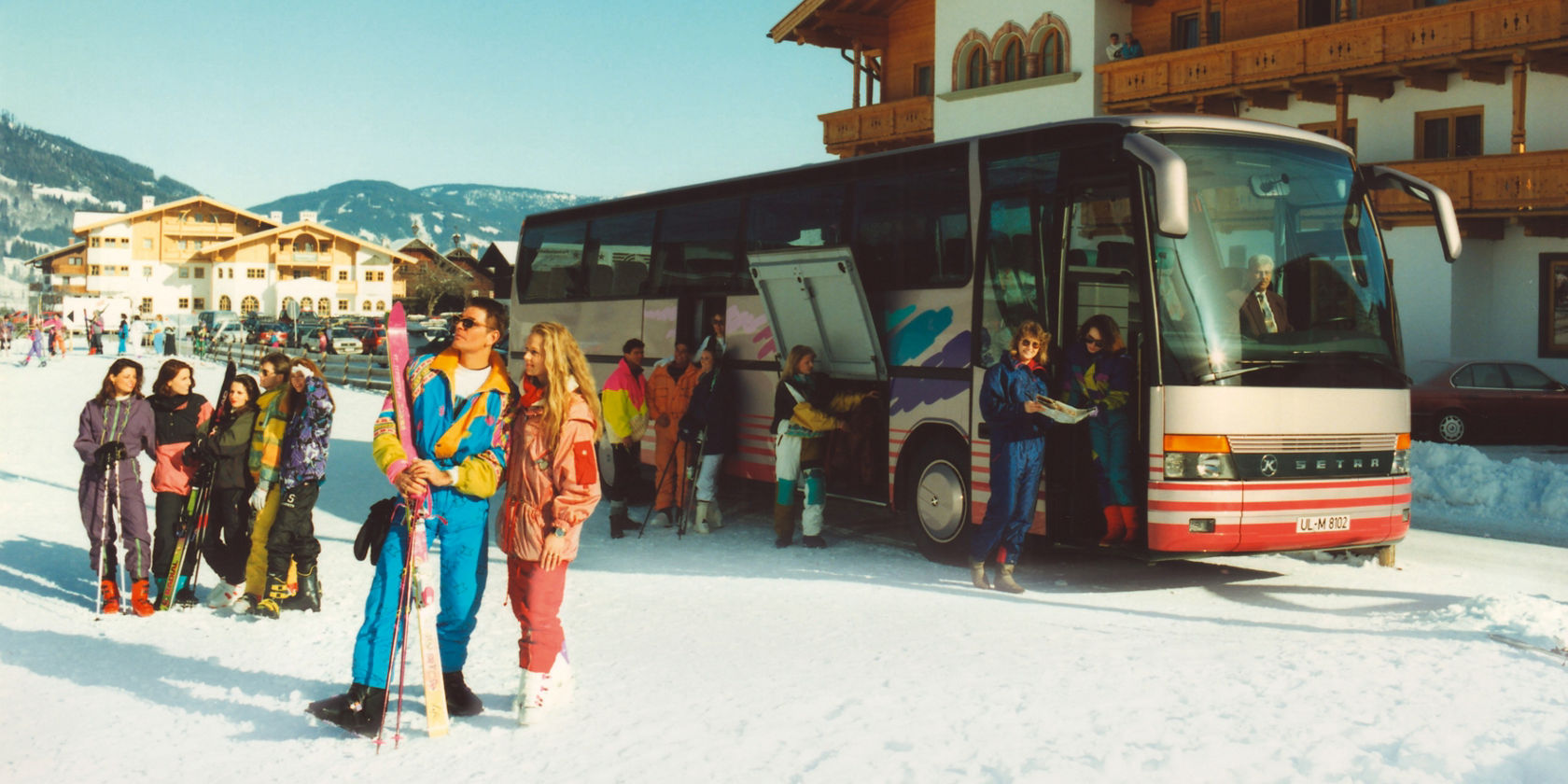 Setra historic touring coach in front of a hotel in the ski area, skiers standing in the snow next to the bus with the luggage compartment open