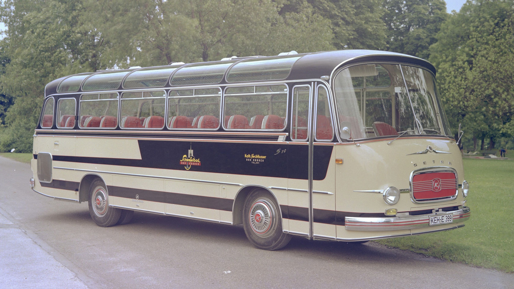 Historic Setra touring coach in beige and dark blue, side view on a parking street with trees in the background