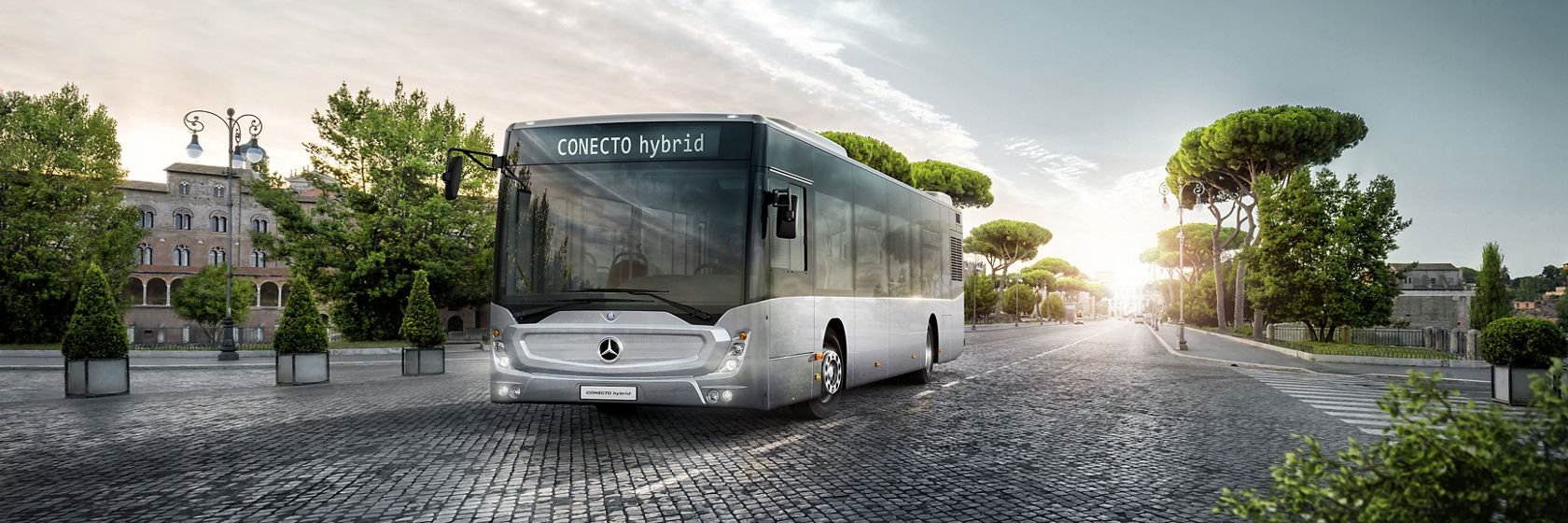 Mercedes-Benz Conecto hibridni gradski autobus na asfaltovanom putu u zelenom, seoskom okruženju.