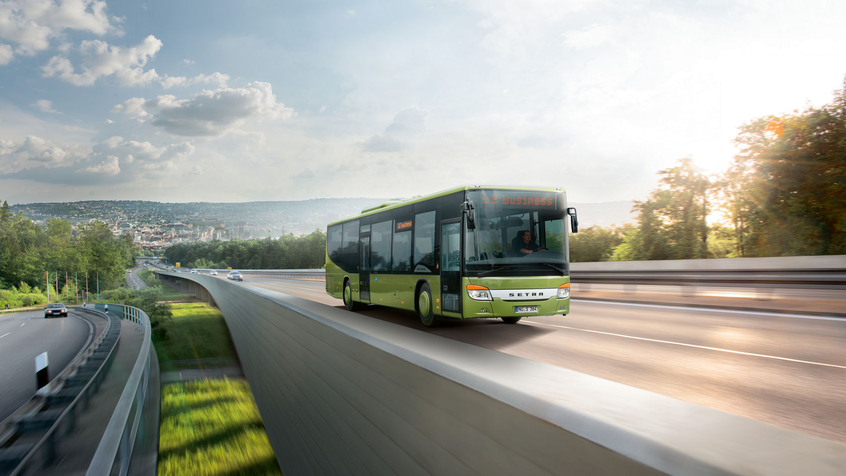 Green Setra MultiClass bus driving on city motorway with view over a valley
