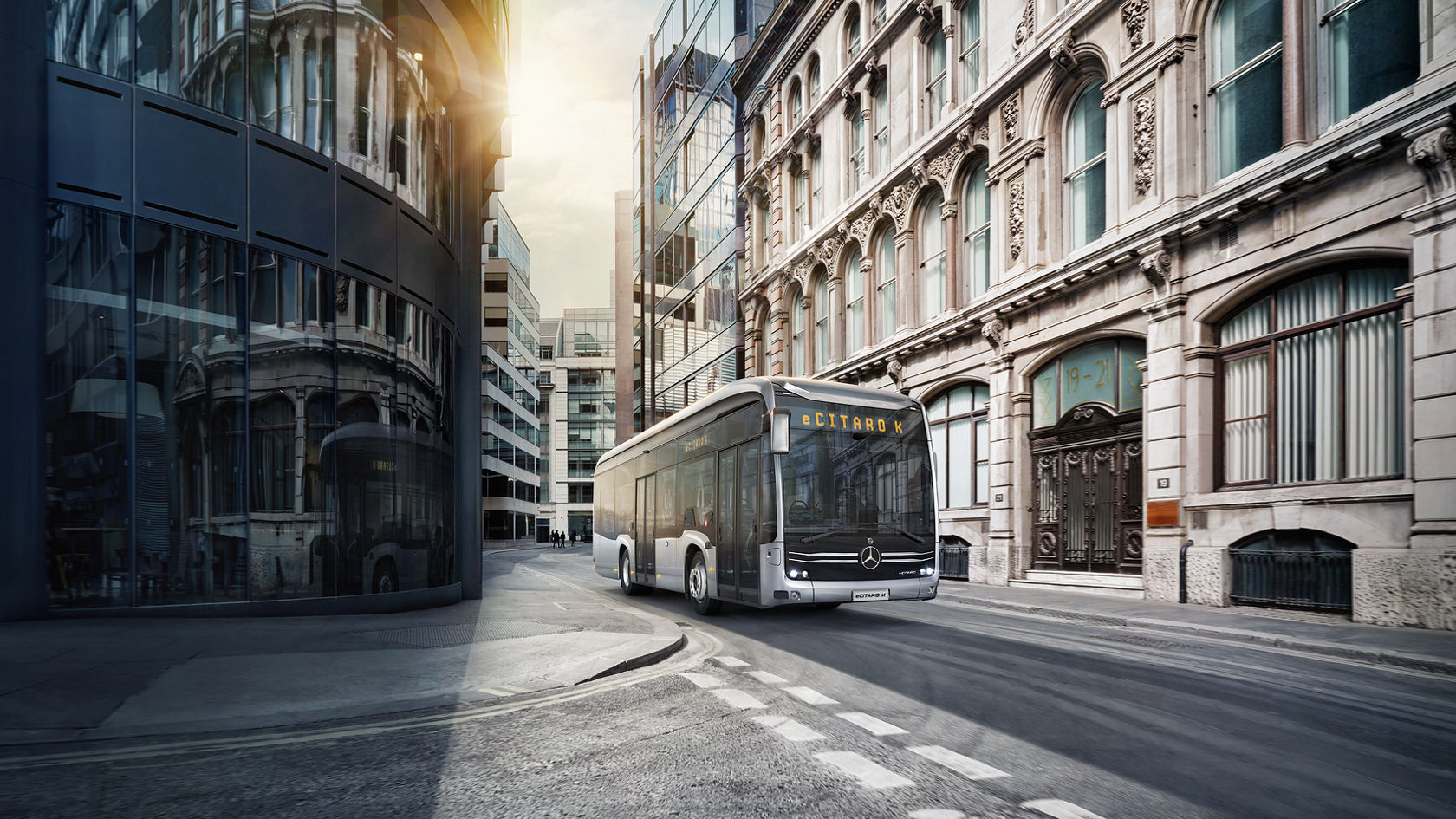 Mercedes‑Benz eCitaro Stadtbus fährt durch Innenstadtstraße, umgeben von Glasfassaden und Altbauten