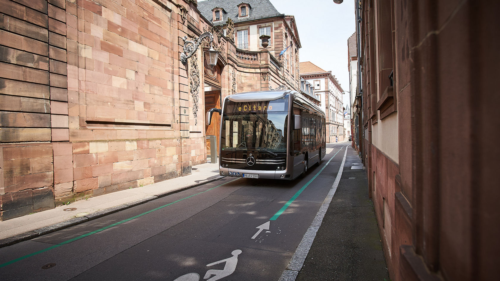 Mercedes-Benz eCitaro Stadtbus in einer engen Altstadtstraße, neben markiertem Radweg und Sandsteinfassaden