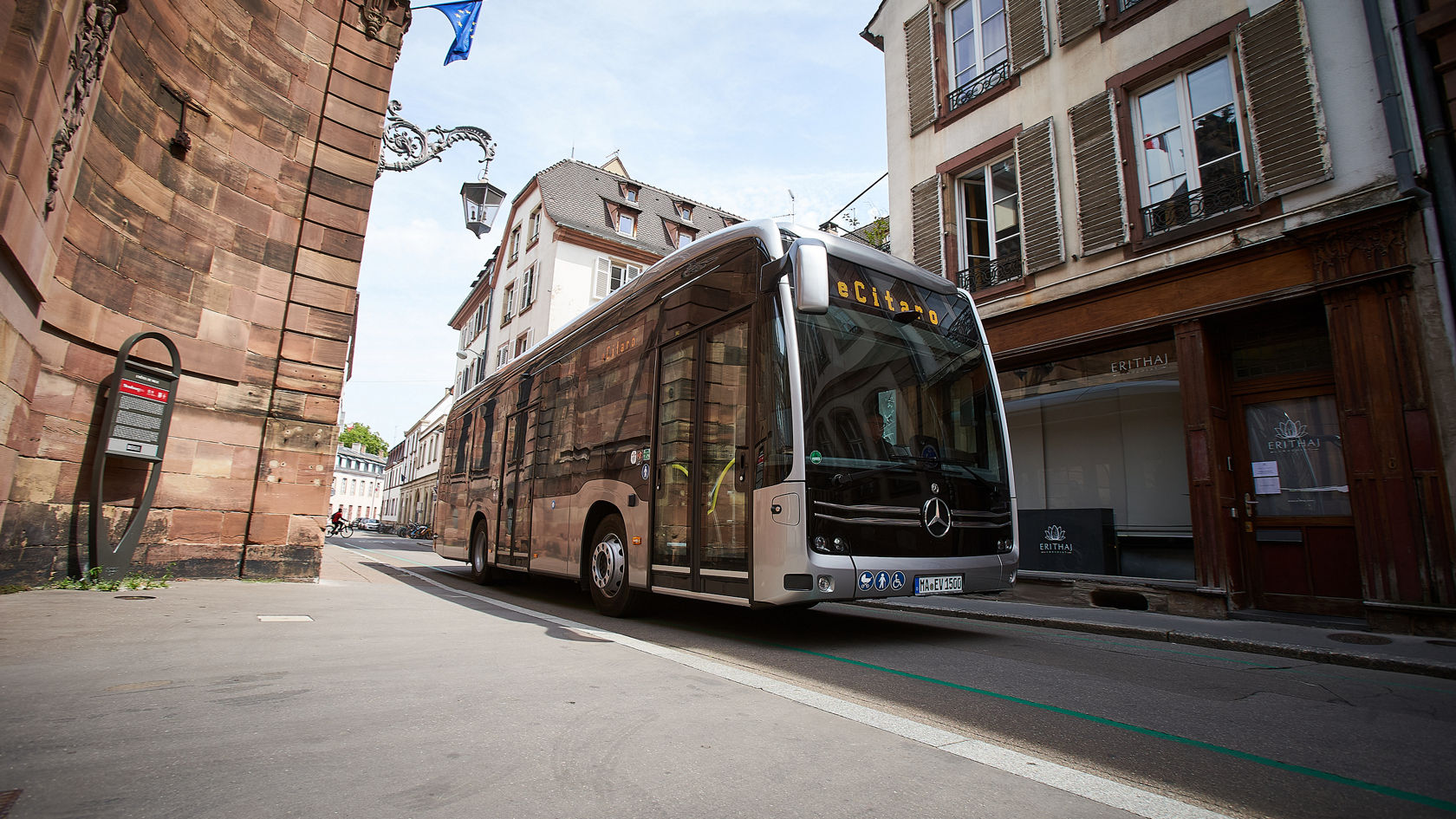 Mercedes‑Benz eCitaro Stadtbus in Altstadtstraße, mit historischen Fassaden und Haltestelle am Straßenrand