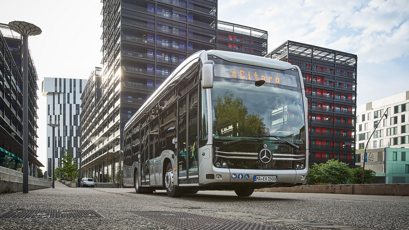 Mercedes-Benz eCitaro Stadtbus in einer Innenstadt zwischen Hochhäusern, Frontansicht mit LED-Zielanzeige