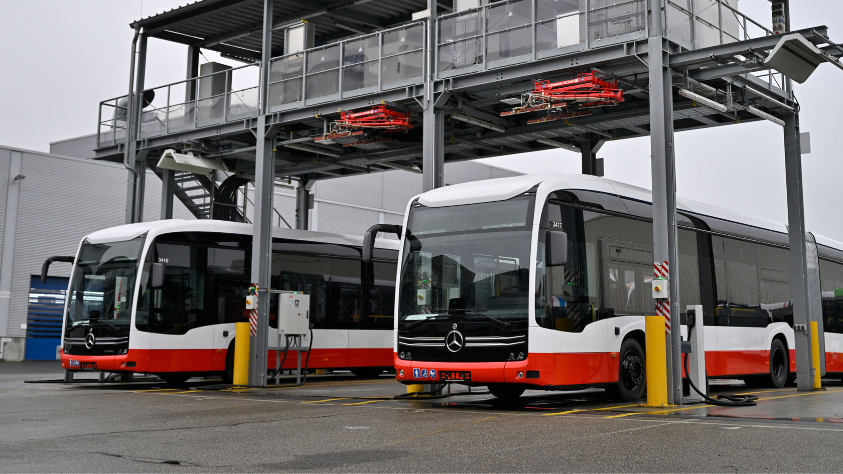 Dos autobuses urbanos Mercedes-Benz eCitaro en la estación de carga del depósito bajo un tejado en el depósito
