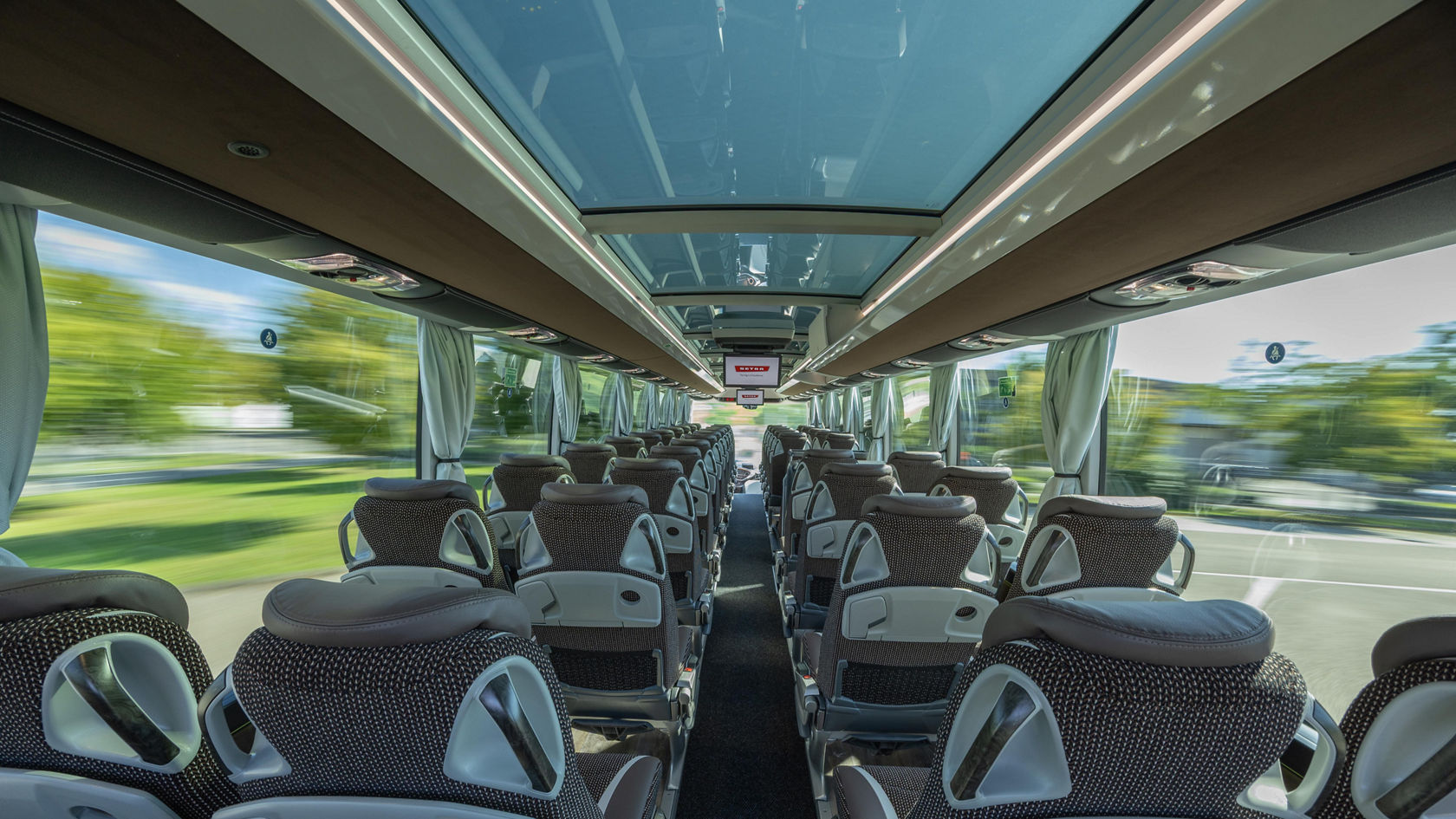 Autobus da turismo Setra TopClass, abitacolo con file di sedili e ampio tetto panoramico in vetro, vista in avanti attraverso il corridoio centrale
