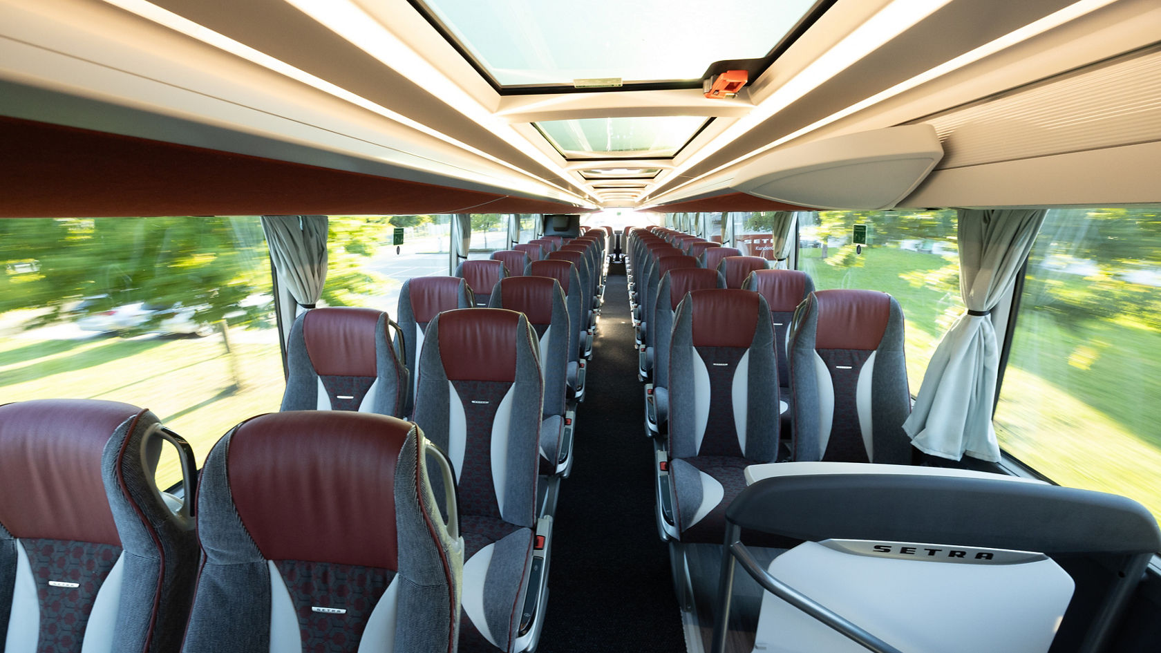 Blick durch den Fahrgastraum des Oberdecks eines Setra S 531 Doppelstock-Reisebusses mit Sitzreihen, Mittelgang, LED-Beleuchtung und Panorama-Glasdach