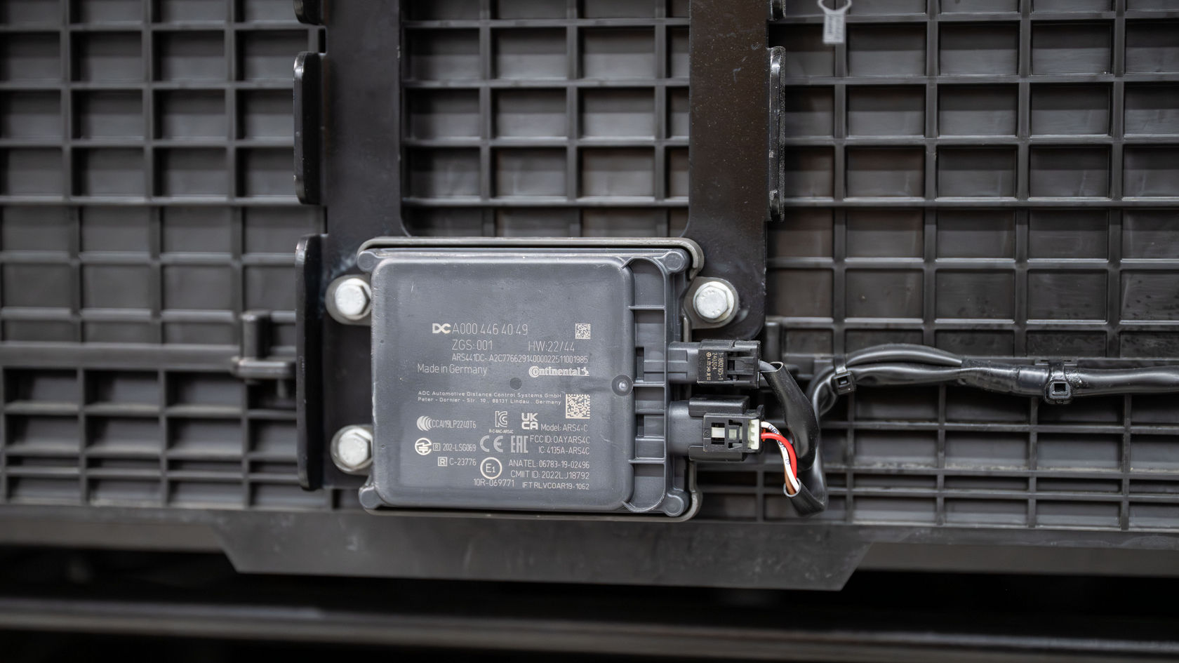 Electronic control unit on the vehicle module with cable connection, mounted in front of a black radiator grille