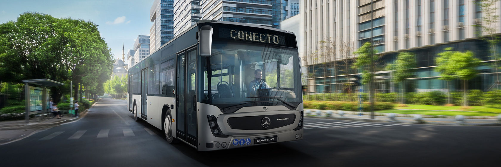 Mercedes-Benz Conecto gradski autobus kroz moderan, zeleni centralni grad sa visokim kancelarijama u pozadini.