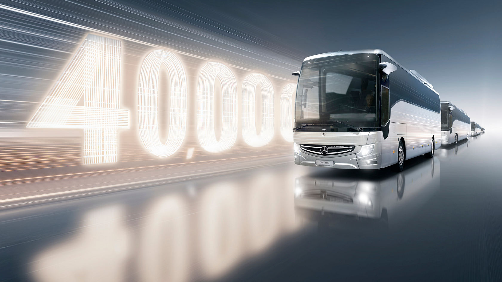 Mercedes-Benz langrutebuss Tourrismo foran lysende "40.000"-grafikk med flere busser på rad på speilflate