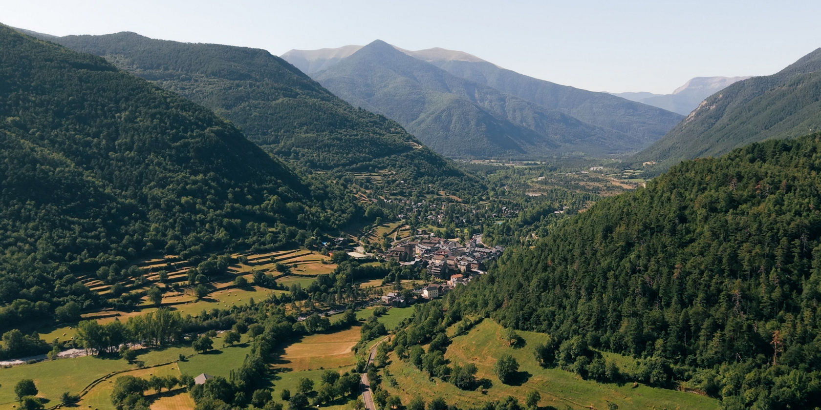 Weitläufige Berglandschaft mit Tal, Straße und kleinen Ortschaften.