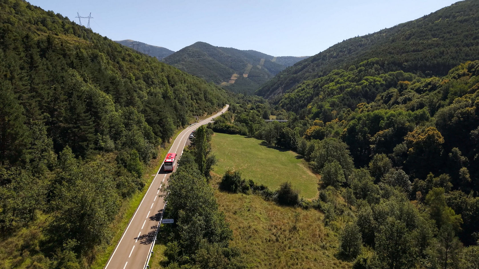 Mercedes-Benz Überlandbus Intouro aus der Vogelperspektive auf einer Überlandstraße durch bewaldete Berglandschaft.