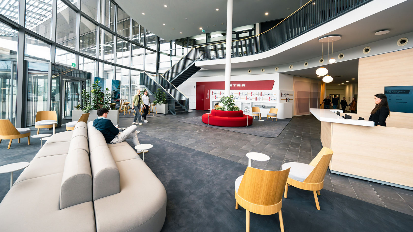 Interni moderni e luminosi del Centro Clienti Setra con lobby aperta, posti a sedere, scale e facciata in vetro.