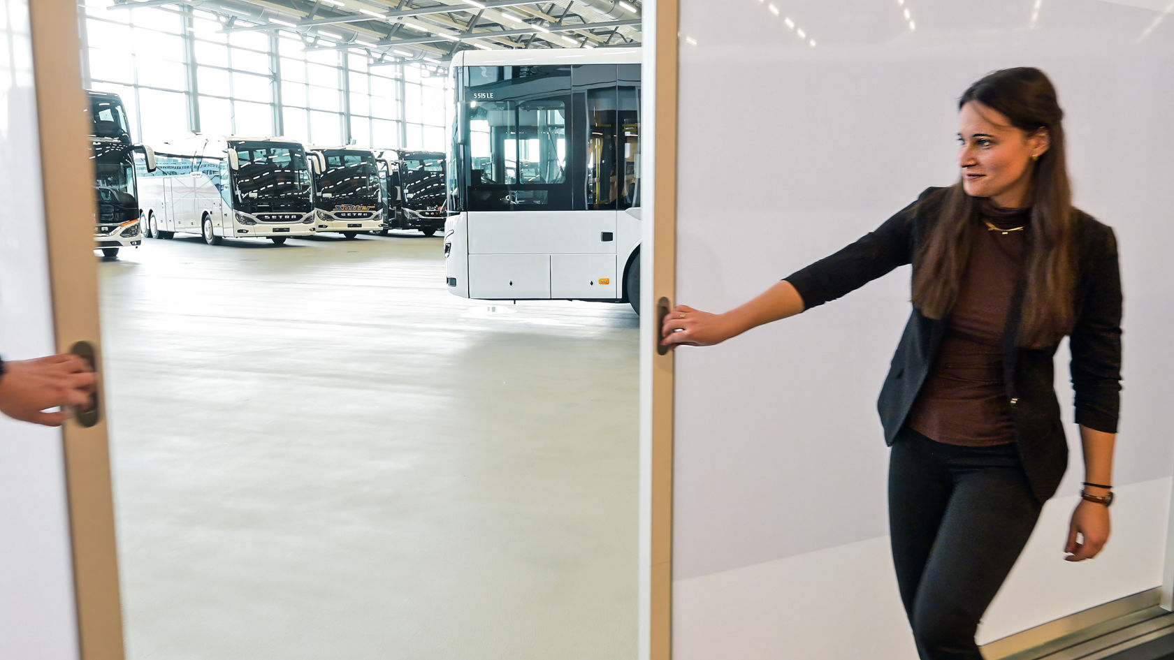 Vista del capannone di consegna adiacente al Centro Clienti Setra con diversi autobus e un accesso aperto in primo piano.