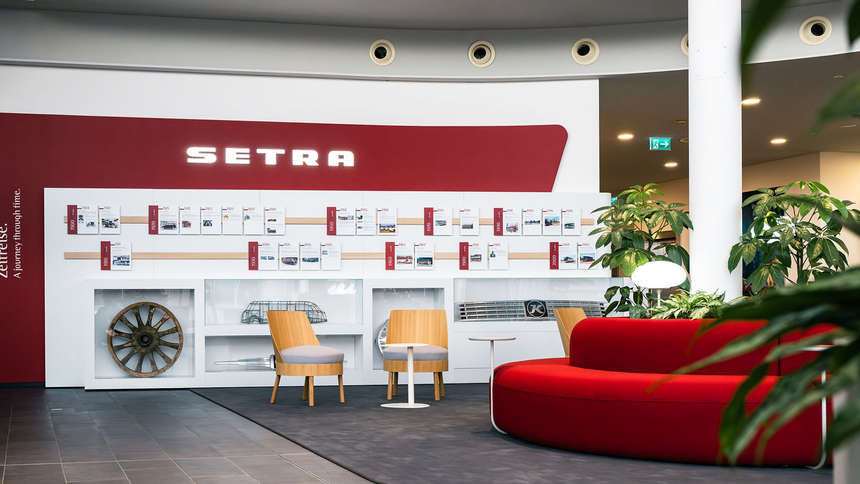 Area espositiva nel Centro Clienti Setra con parete del marchio, espositori di design, sedili e moderna architettura degli interni.