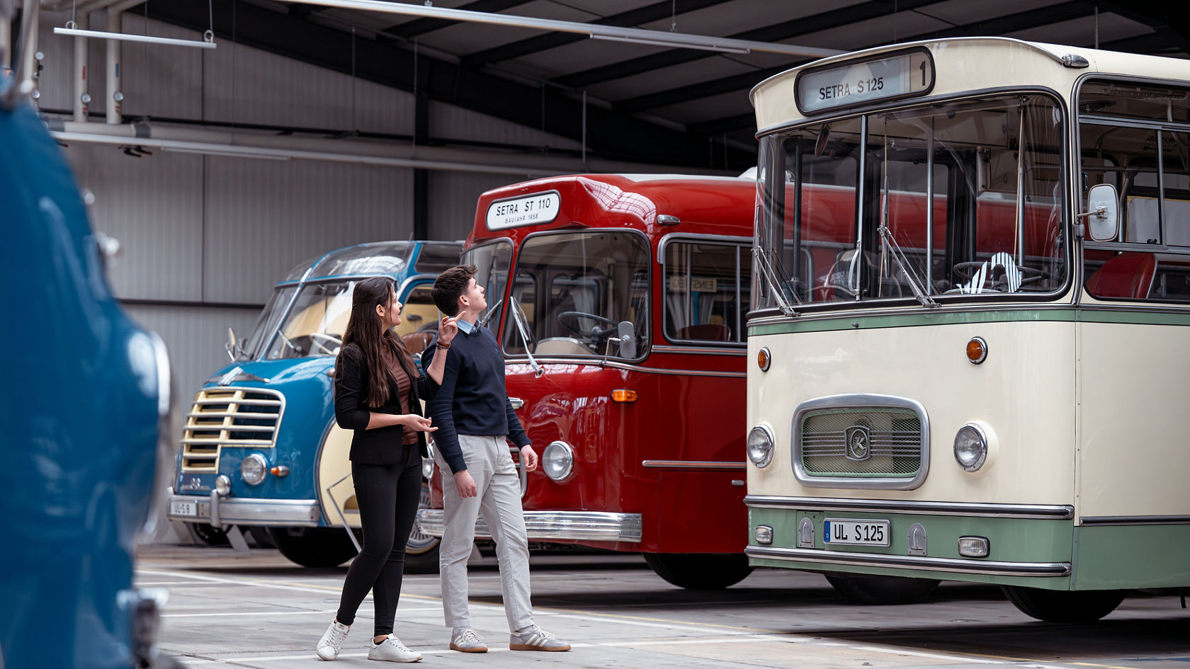 Bezoekers in de Kässbohrer Halle voor historische Setra lijnbussen, waaronder de Setra S 125 en Setra ST 110