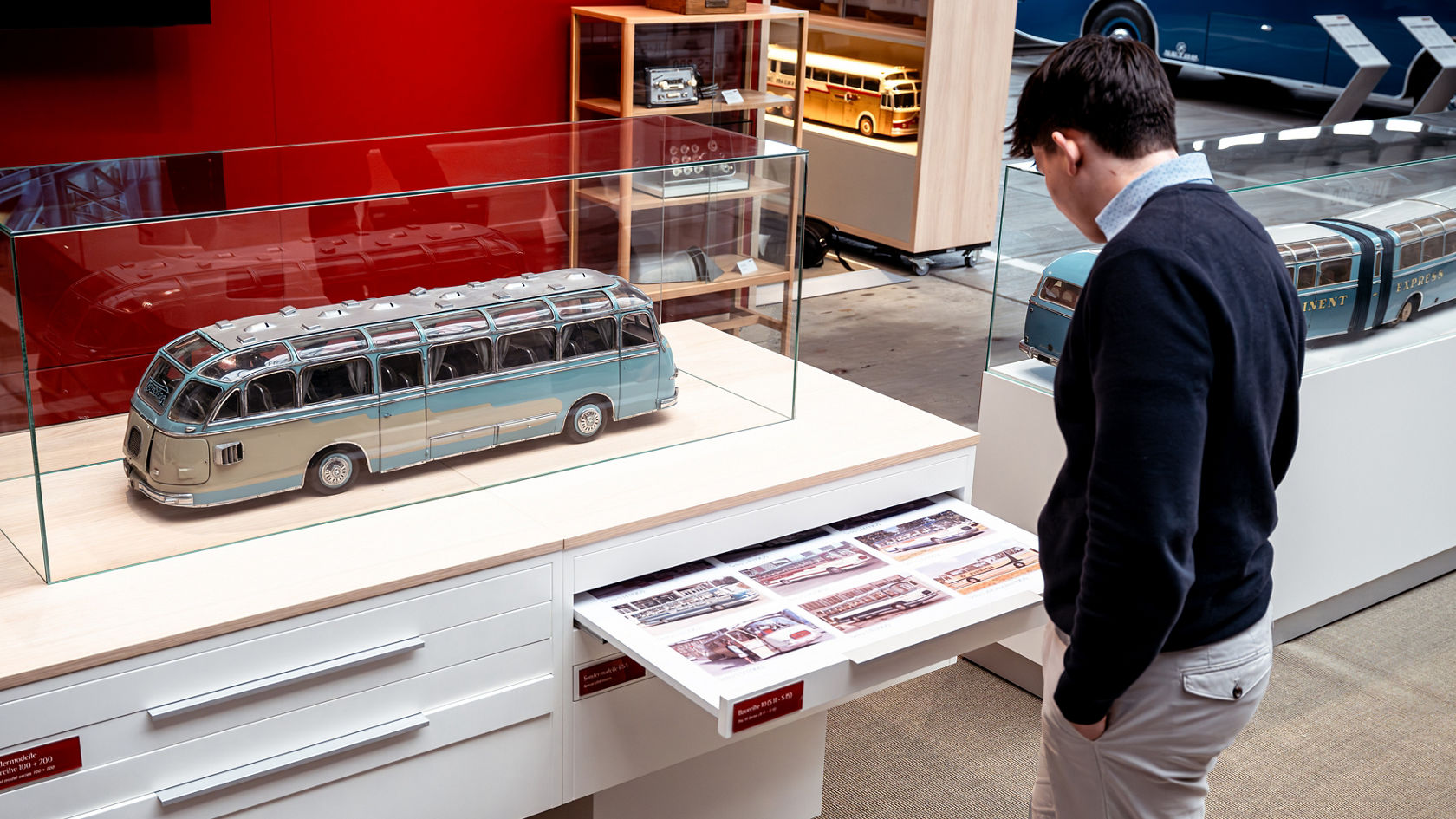 Bezoeker bekijkt in de Kässbohrer Halle een historische Setra bus als model in glazen vitrine met informatiebord
