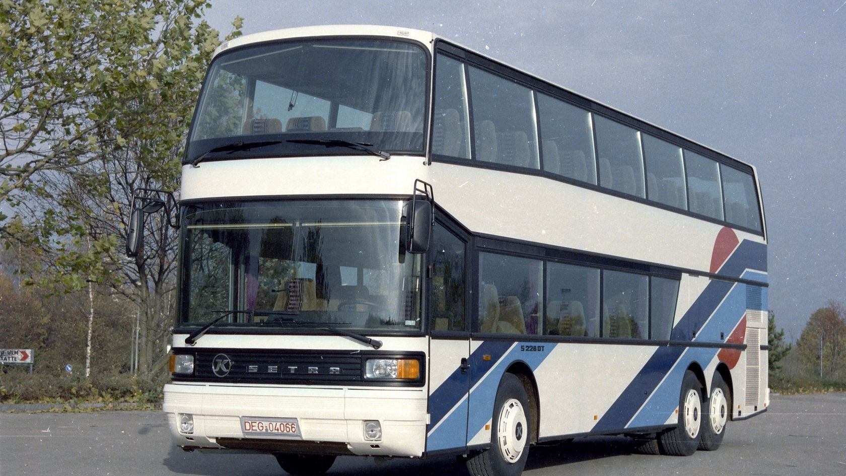 Setra double-decker coach in white with light and dark blue stripes, shot at an angle from the front on a parking POI overlay