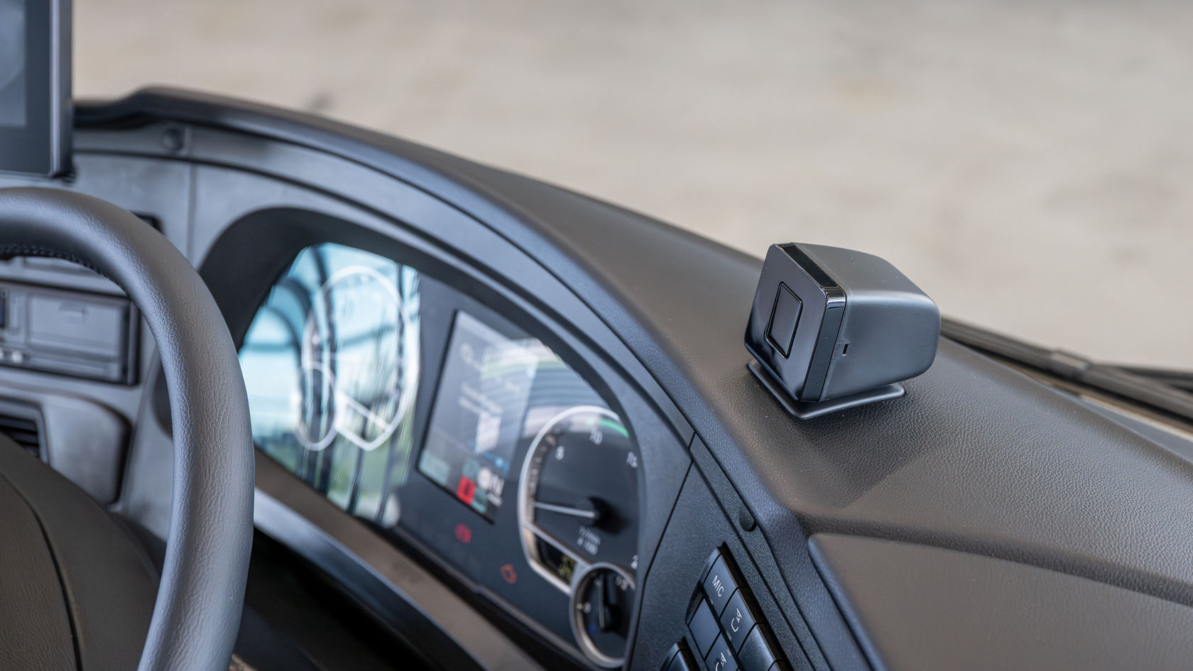 Kompakt kamera på instrumentpanelen i en Setra turistbuss, bredvid det digitala kombiinstrumentet på förararbetsplatsen. Kameran kontrollerar förarens uppmärksamhet och avger en eventuell varning via Attention Assist.