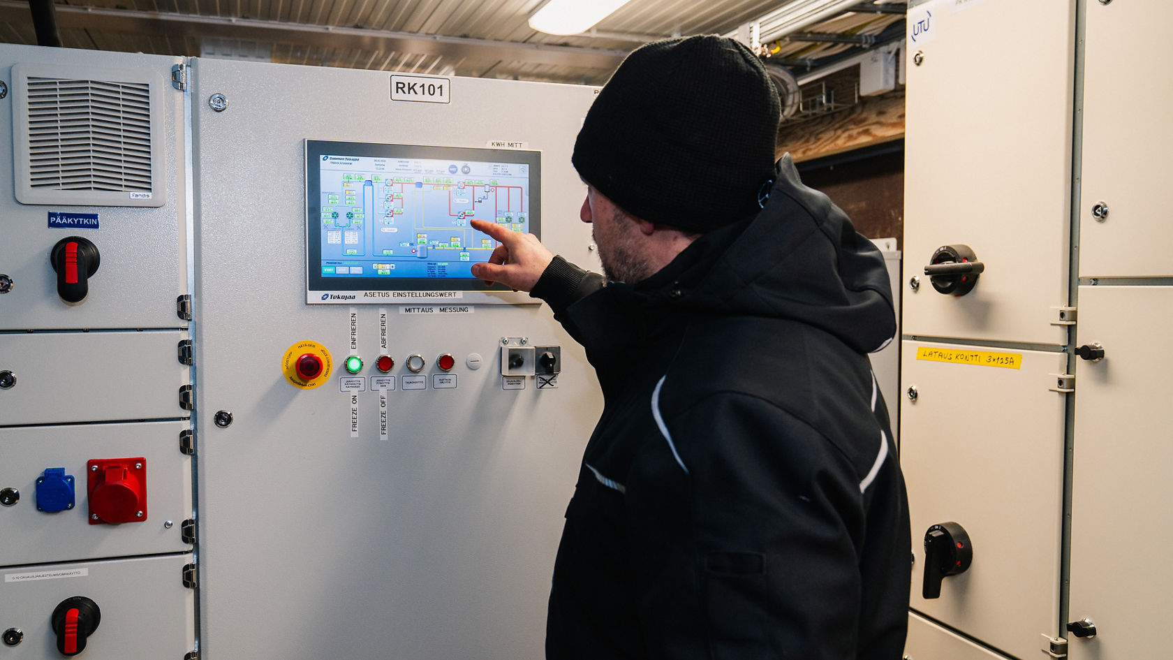Un technicien de Daimler Buses utilise une armoire de commande avec écran tactile et voyants de contrôle dans un local technique