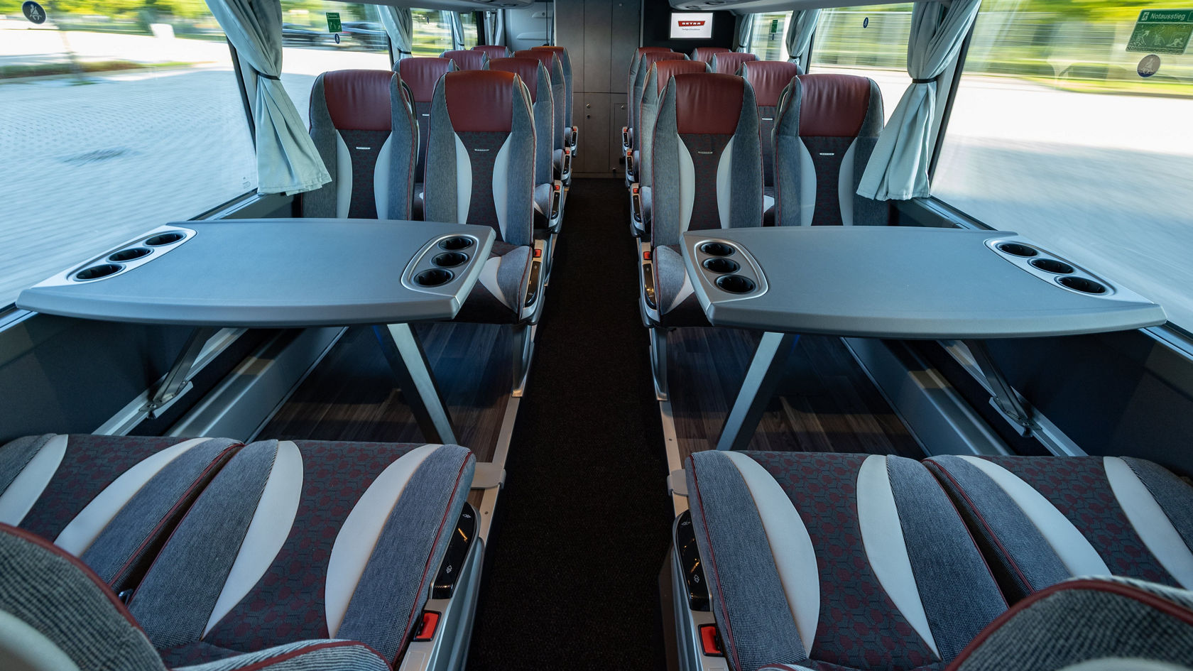 Innenraum eines Setra Doppelstock Reisebusses mit Reihenbestuhlung, Vorhängen und Monitor im Heckbereich