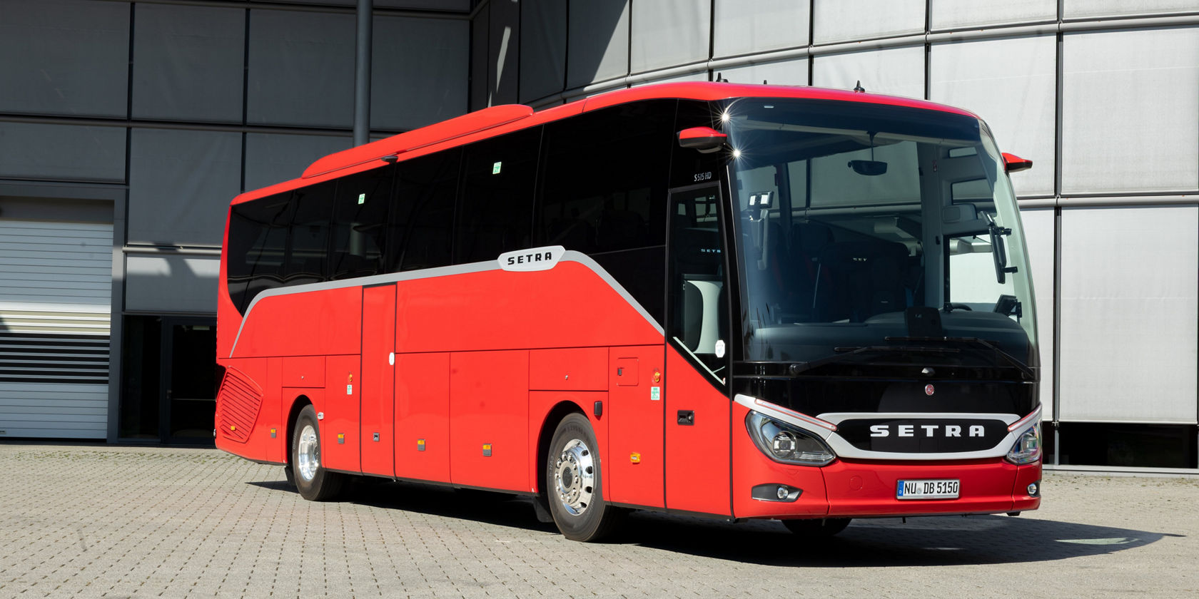 Autocarro de turismo Setra ComfortClass vermelho em frente a um moderno edifício de vidro, vista frontal com para-brisas grande