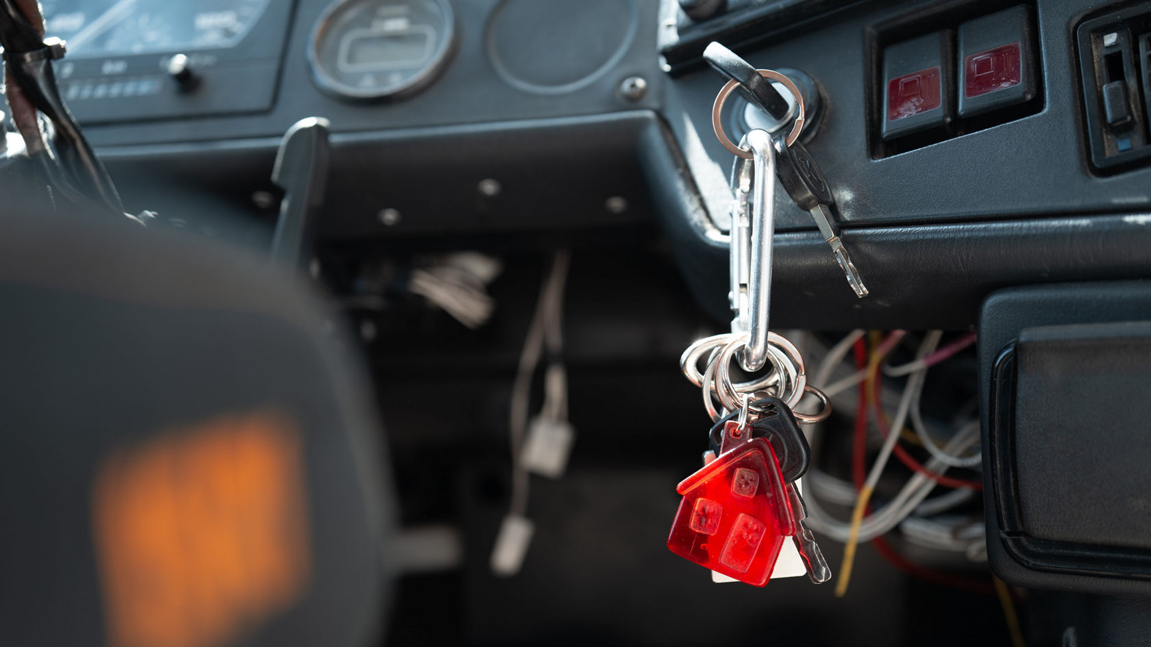 Détail du poste de conduite Setra : clé de contact avec porte-clés et porte-clés rouge, à côté contacteurs et câblage sur la planche de bord