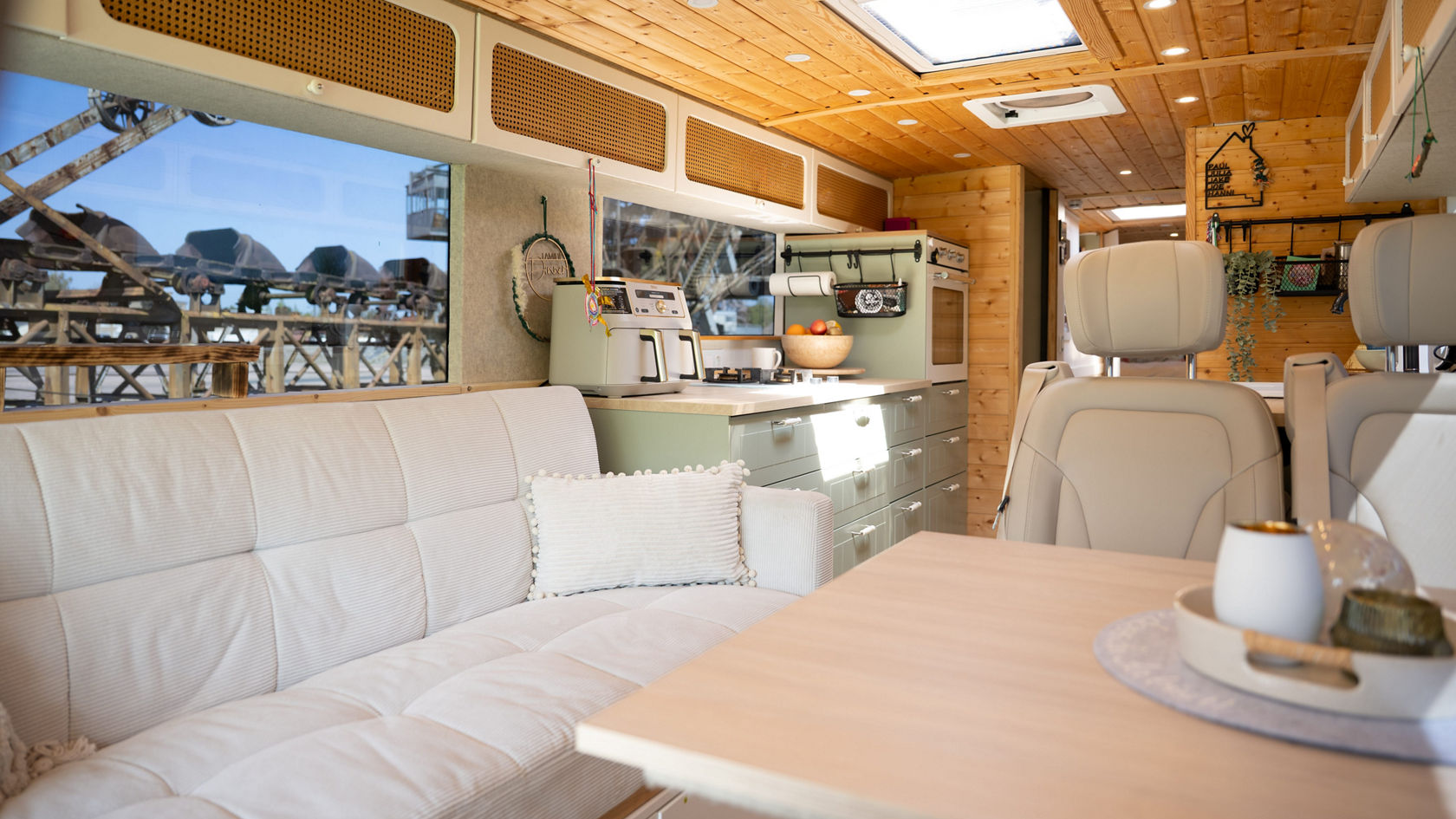 Habitacle d’une transformation de camping-car Setra avec plafond en bois, banquette, table et bloc-cuisine avec espace de rangement et fenêtre de toit