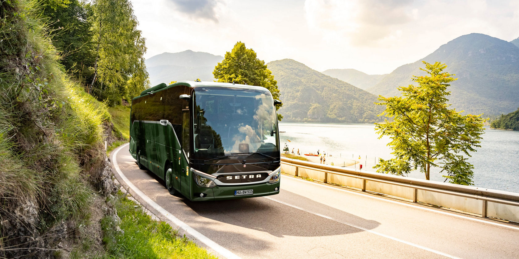 Autocarro de turismo Setra ComfortClass verde percorre uma estrada costeira sinuosa ao longo de rochas íngremes, à direita um curso de água