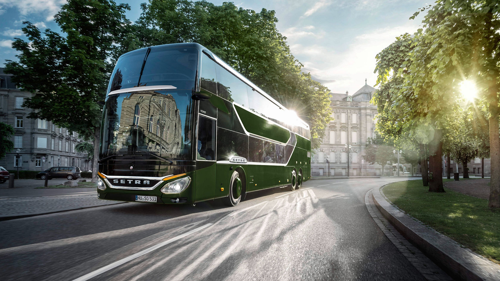 Green Setra double-decker coach driving through an alley in the city, with historic buildings in the background