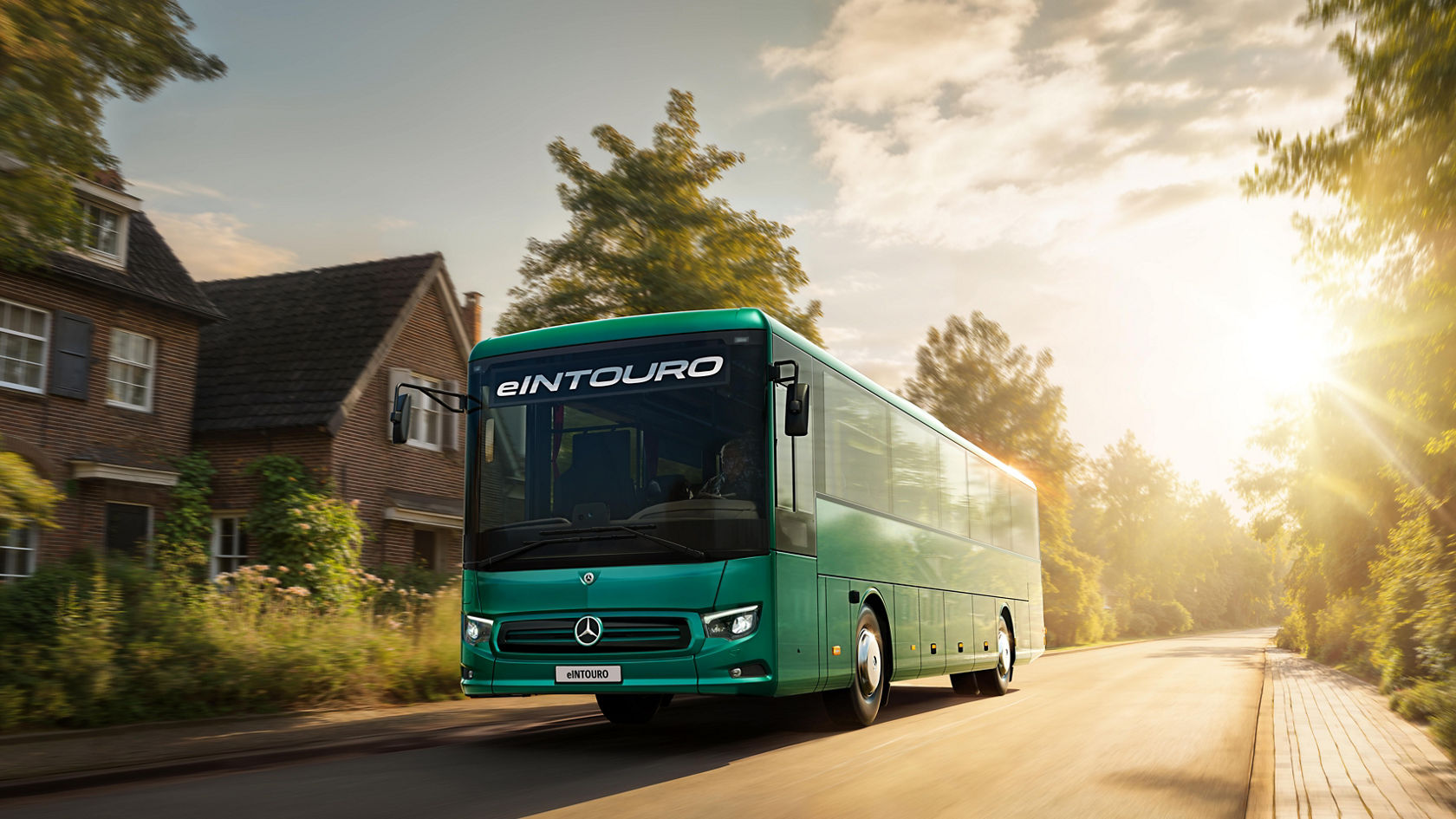 Mercedes-Benz eIntouro inter-city bus driving through residential area with trees and houses in low sun