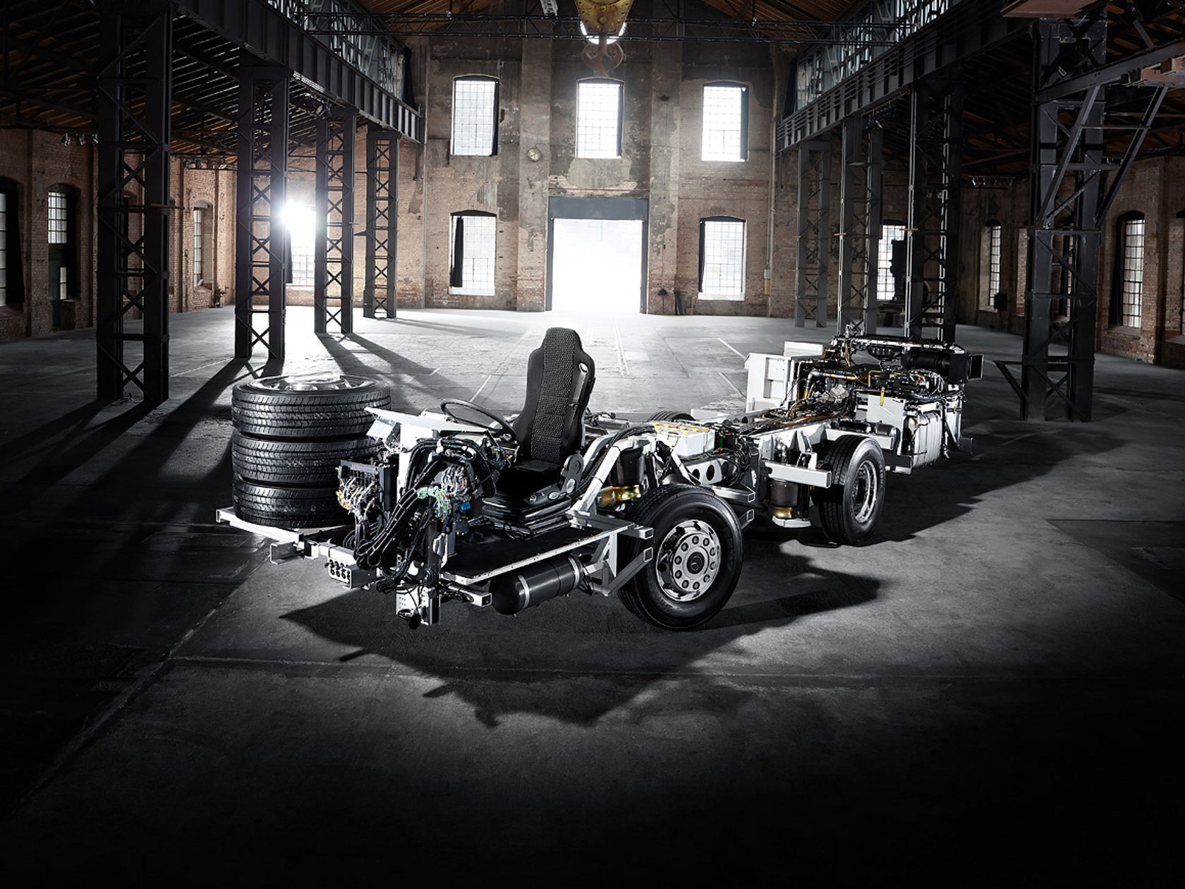 Mercedes-Benz OC 500 RF bus chassis with exposed technology, driver’s seat and stacked tires in a large industrial hall